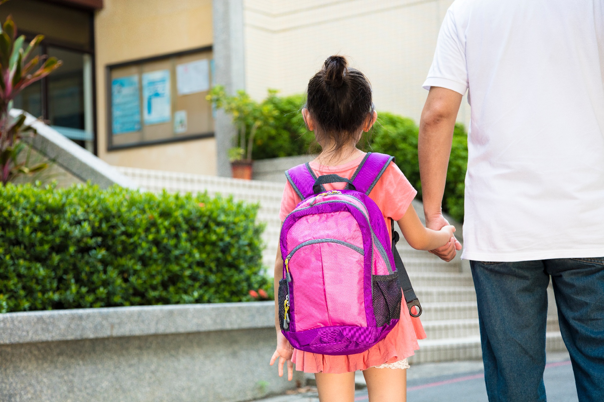 Female student walking into school with her dad