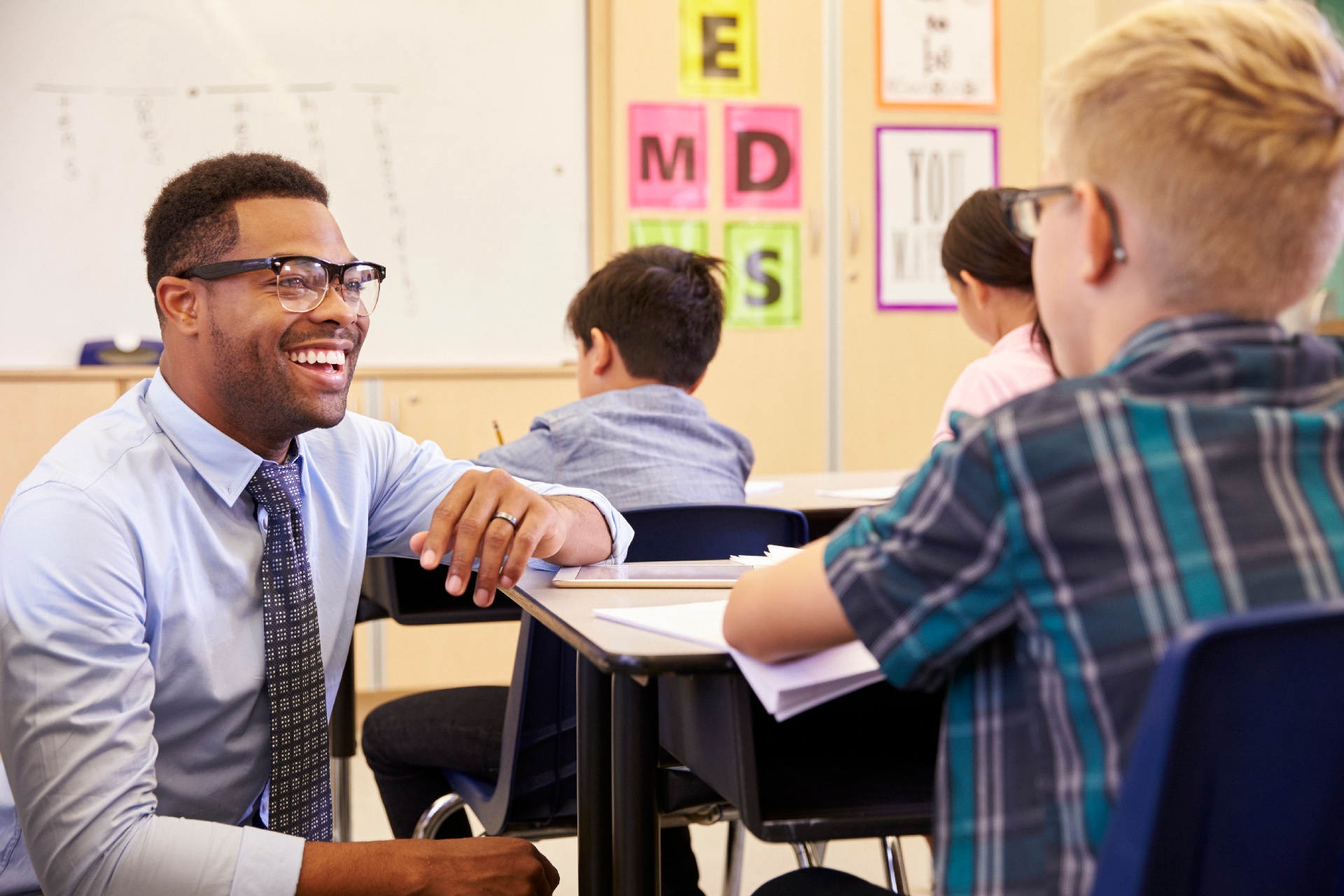 Male teacher smiling, crouching down beside young male student