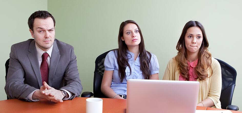 three staff members in a meeting with strange facial expressions