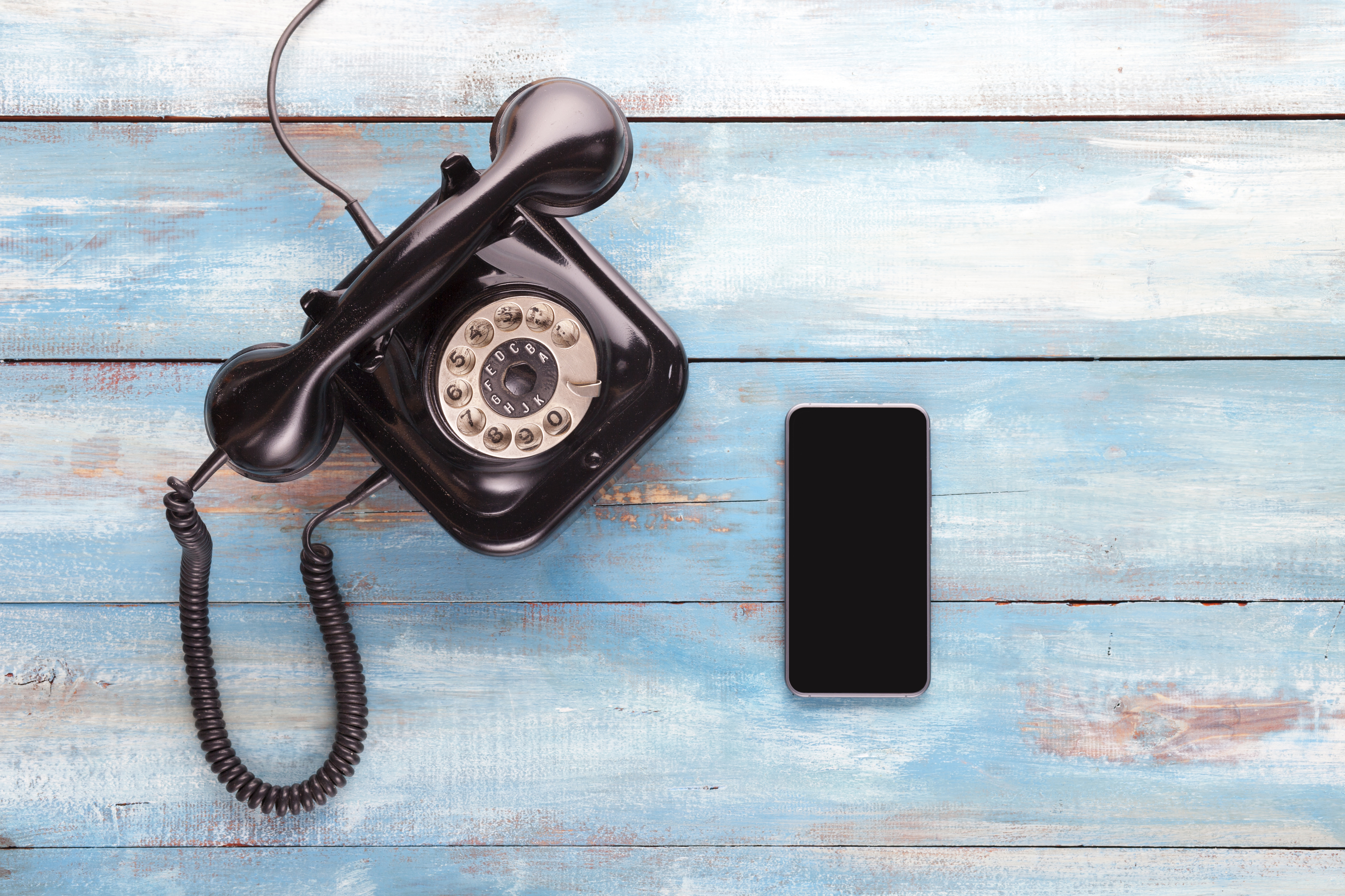 Photo of an old rotary telephone next to a smartphone